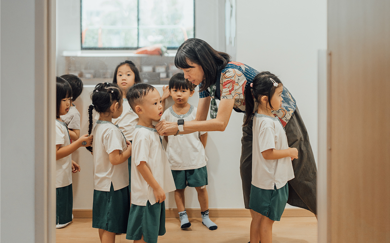 Little Seeds teacher assisting preschoolers as they prepare for class.