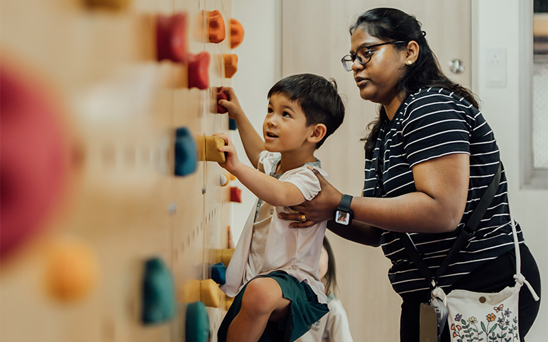 Preschooler developing problem-solving skills on indoor rock climbing wall.