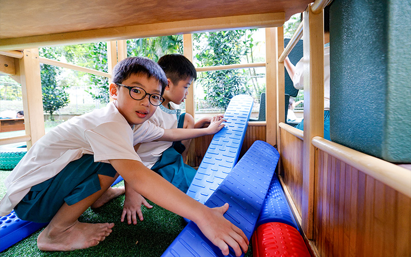 Boys sharing play equipment outside.