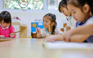 Little Seeds early years students interacting during writing activity.