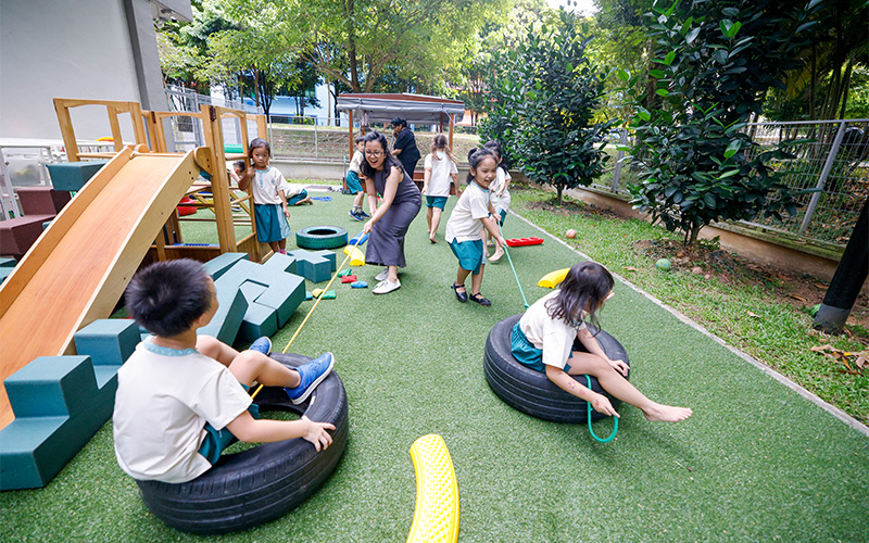 Little Seeds kids and teacher playing together in playing ground.