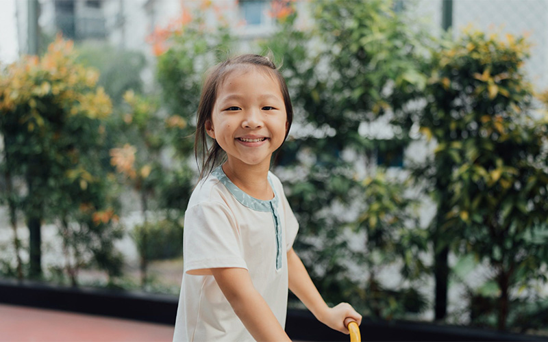 Smiling preschool child playing outdoors at Little Seeds school.