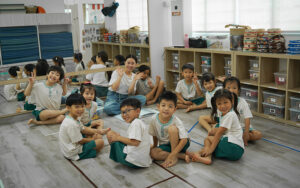 Teacher and preschool children sitting on floor during group activity.