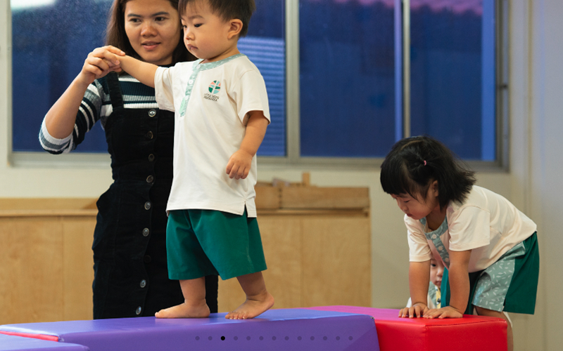 Teacher guiding a child through physical play at Little Seeds.