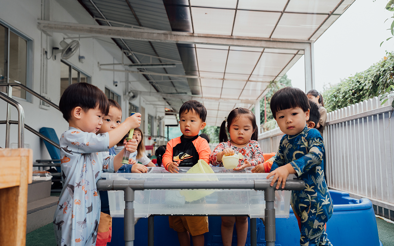 Toddlers engaging in collaborative outdoor water play.